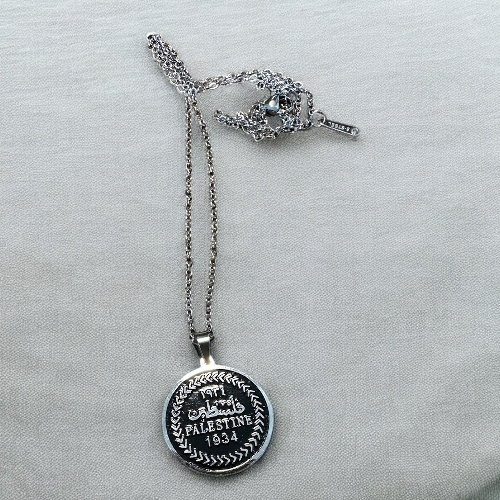 Silver necklace with a pendant on a white cushion Pal 1934