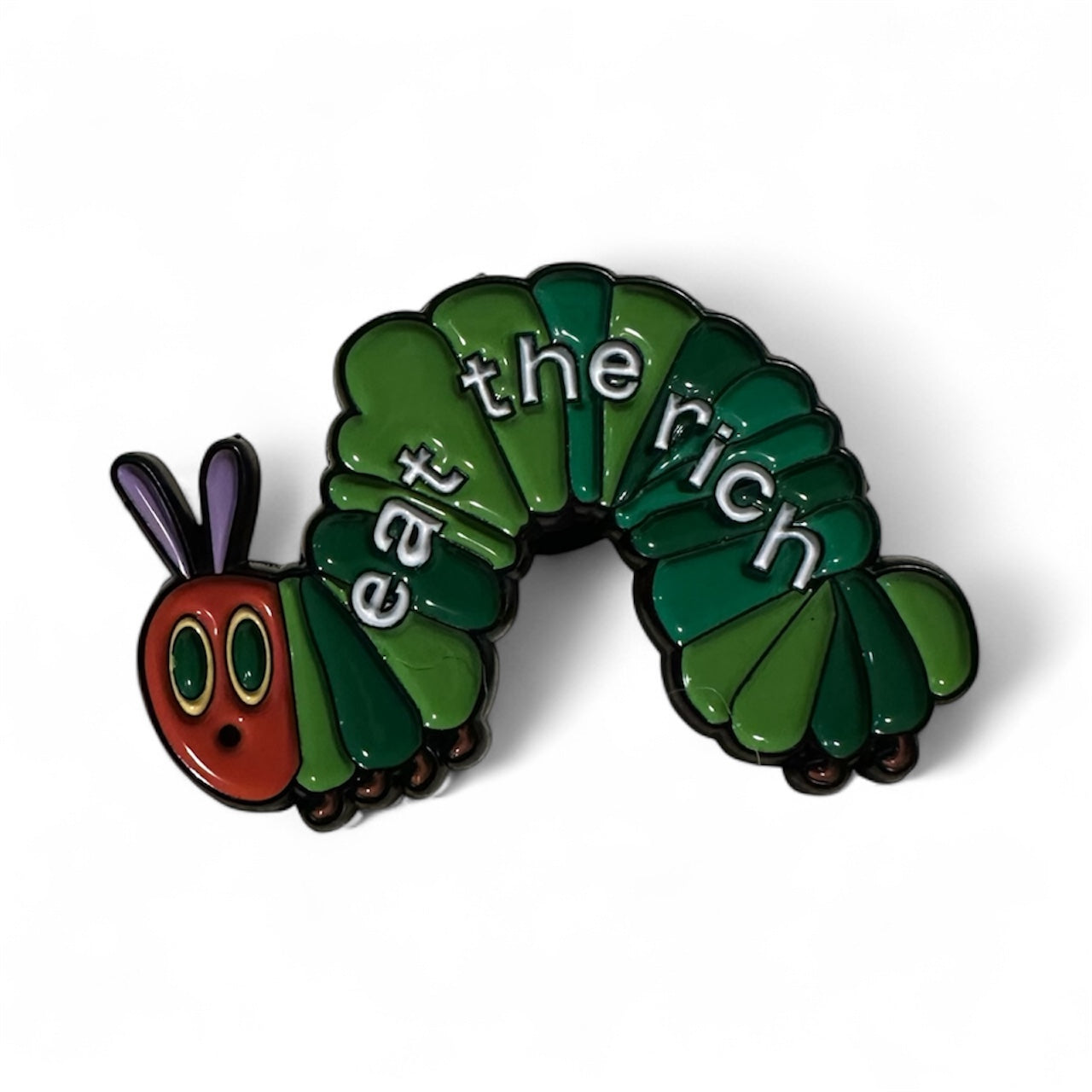 Caterpillar-shaped enamel pin with 'eat the rich' text on a white background